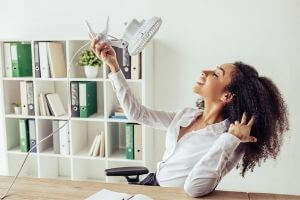 Woman enjoying a personal fan in an office setting, illustrating comfort during warmer months and the importance of efficient cooling solutions.