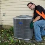 Man in black shirt and gloves servicing air conditioning unit next to building for Easco Air Conditioning and Heating.