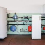 Large white water heater and blue tank with piping in Easco Air Conditioning and Heating's organized HVAC installation.