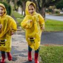 Children wearing yellow raincoats and red boots playing outside, highlighting the importance of keeping dry and comfortable during rainy seasons, relevant to choosing dehumidifiers for home use.