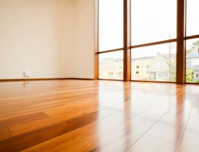 Hardwood floors in a bright, spacious room with large windows, showcasing the importance of moisture control to prevent warping and mold growth.