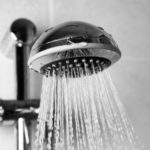 Chrome showerhead with water droplets showcasing cleanliness in HVAC-maintained bathrooms by Easco Air Conditioning.