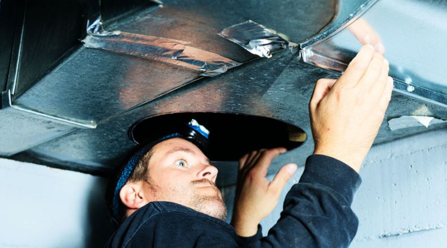 HVAC technician inspecting and repairing air duct system for improved energy efficiency and indoor air quality.