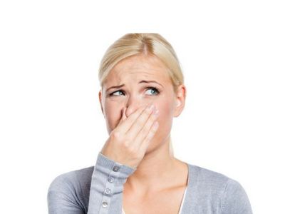 Young woman with blond hair covering her nose, showing concern about unpleasant air quality related to HVAC issues.