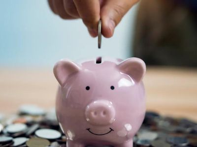 Pink piggy bank with a smiling face, showing coins being inserted, symbolizing savings for HVAC repair and replacement.