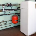 Refrigerator and industrial pipes in an HVAC workspace with a red gas cylinder, showcasing practical air quality solutions.