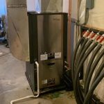 Water heater with metallic finish and plumbing pipes, essential for HVAC systems by Easco Air Conditioning and Heating.