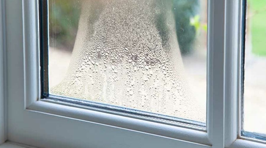 Condensation droplets cover the inside of a double-glazed window.