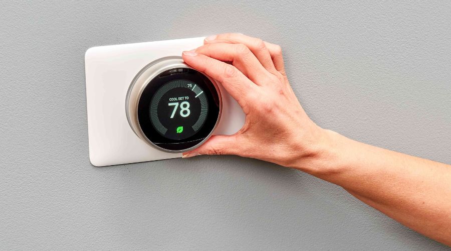 Hand adjusting a smart thermostat displaying a temperature of 78°F, emphasizing energy efficiency and modern HVAC technology.