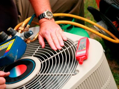 Technician inspecting air conditioning unit with gauges and thermometer, emphasizing HVAC maintenance for improved air quality and allergy reduction.