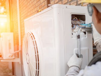 Technician performing maintenance on a heat pump unit, showcasing HVAC repair work and energy-efficient heating and cooling solutions.