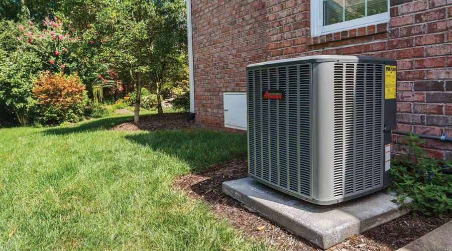 Air conditioning unit outside a house with brick wall and landscaping, branded by Easco Air Conditioning and Heating.