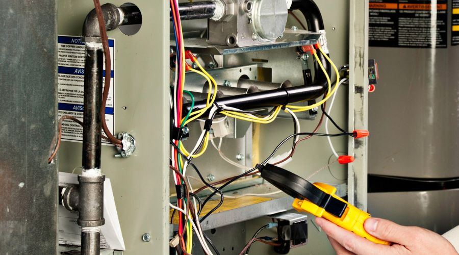 Technician using a multimeter amid colorful wires and HVAC components for Easco Air Conditioning and Heating services.