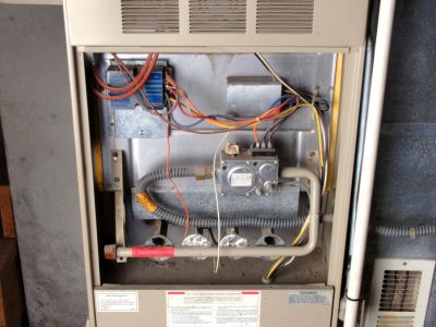 Interior view of a furnace showing essential components like gas valve, wiring, and inspection panels, illustrating the importance of professional heater maintenance for safety and efficiency.