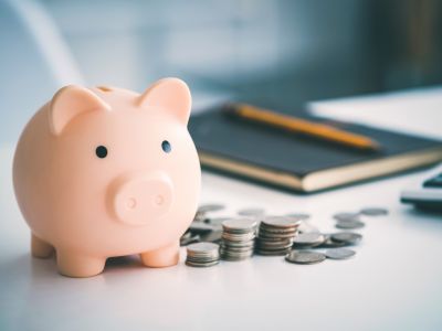 Piggy bank surrounded by coins, symbolizing savings and reduced cooling costs associated with upgrading to a new, energy-efficient air conditioning unit.
