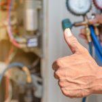 Hand giving a thumbs-up gesture in front of HVAC equipment, symbolizing successful air conditioning maintenance and service by Easco Air Conditioning and Heating.